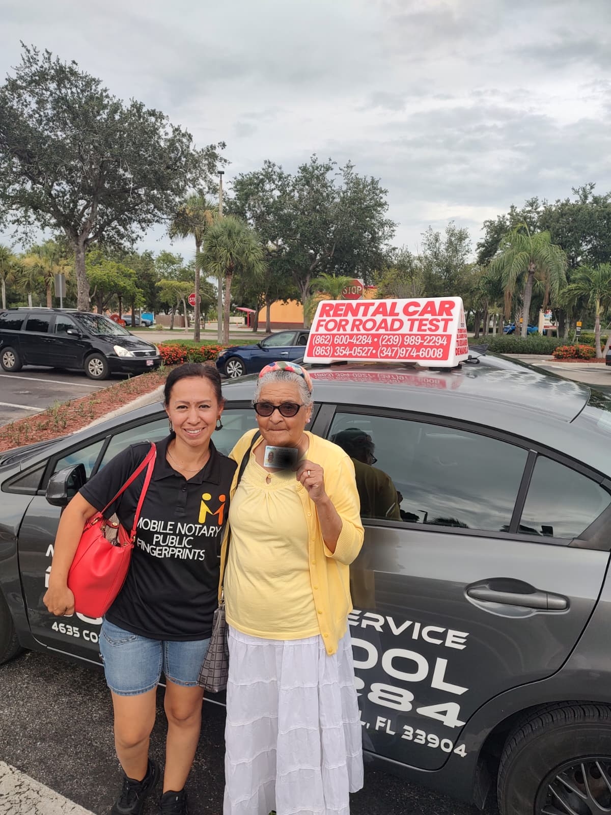 Our instructor with a proud student holding her new Florida driver's license next to the road test car
